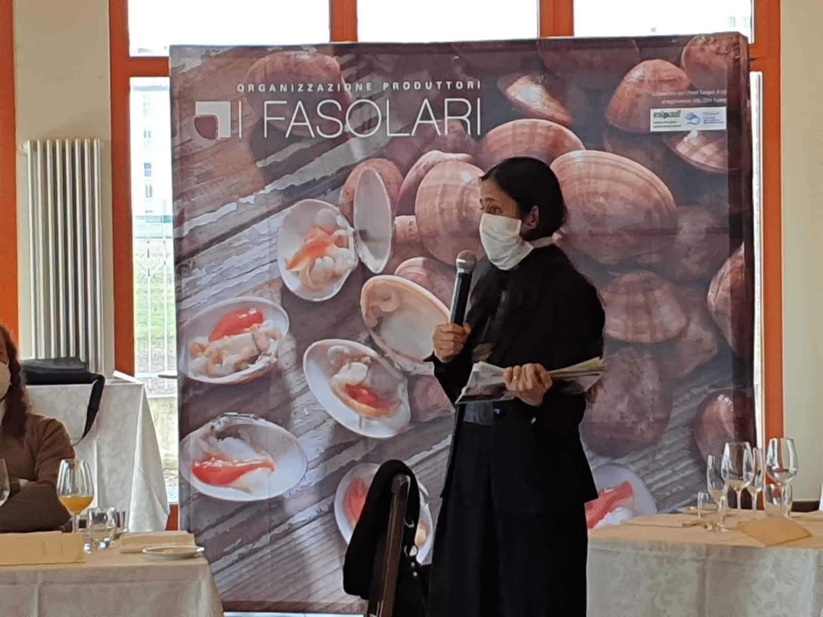 Una relatrice interviene al microfono davanti al pannello de I Fasolari nella sala ENAIP di Chioggia