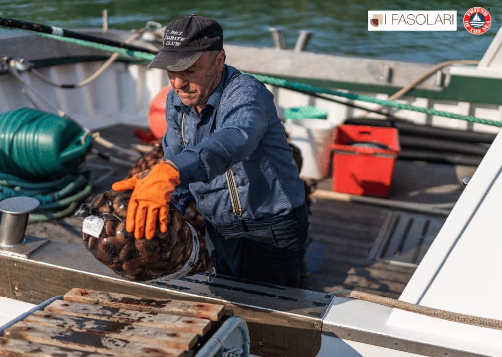 Un pescatore con la retina di fasolari appena raccolti