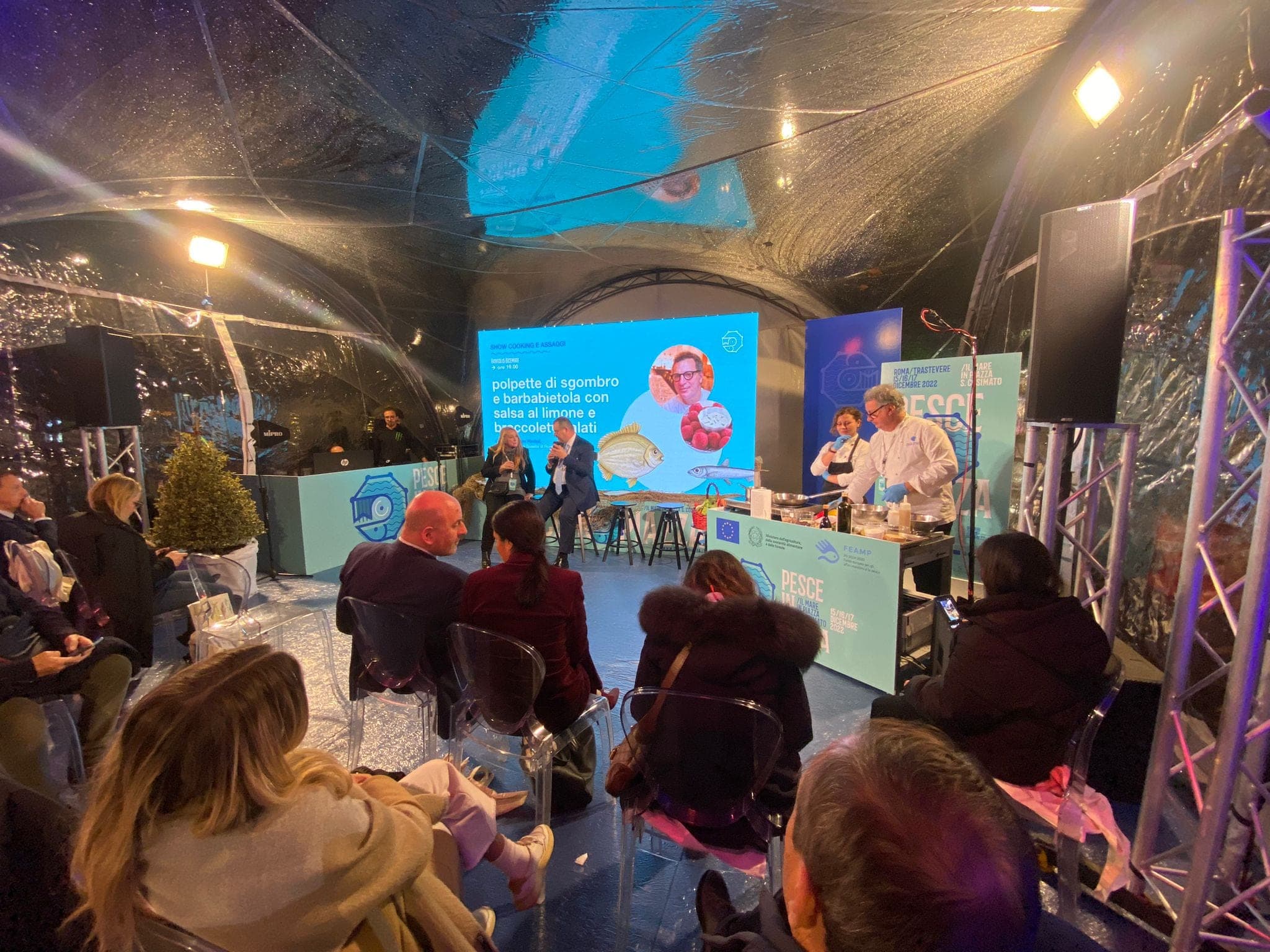Due relatori sul palco del convegno a Pesce in Piazza, a Roma, davanti allo schermo dello show cooking