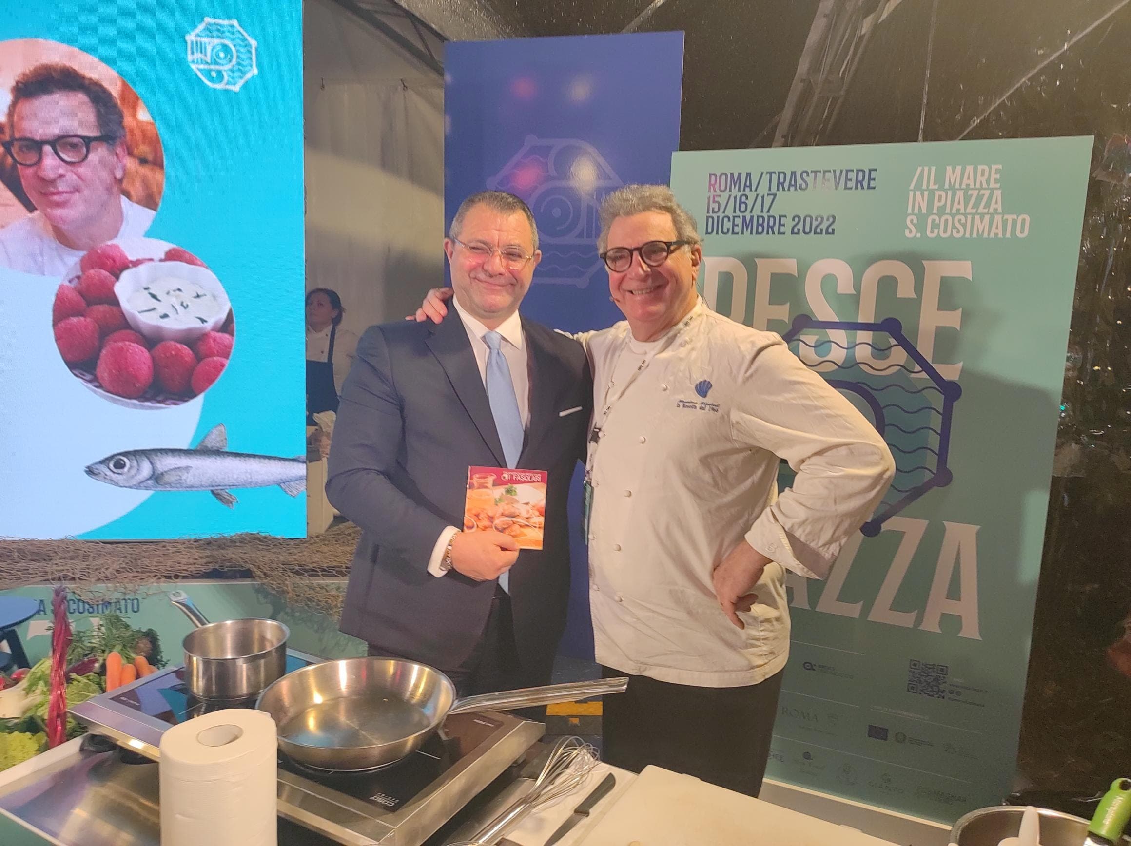 Due partecipanti sorridono davanti alla postazione dello show cooking