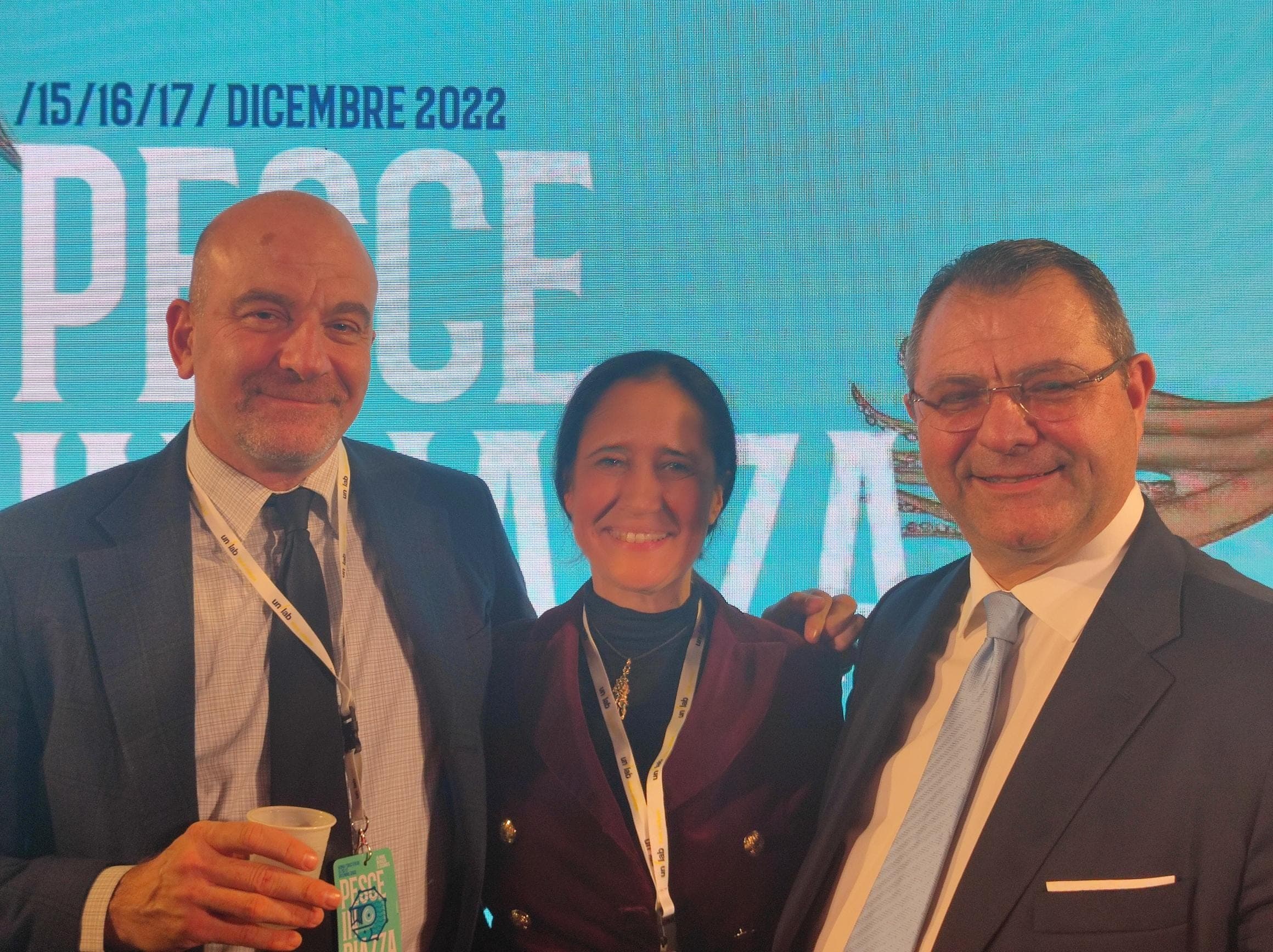 Tre partecipanti davanti allo sfondo dell'evento Pesce in Piazza 2022 a Roma