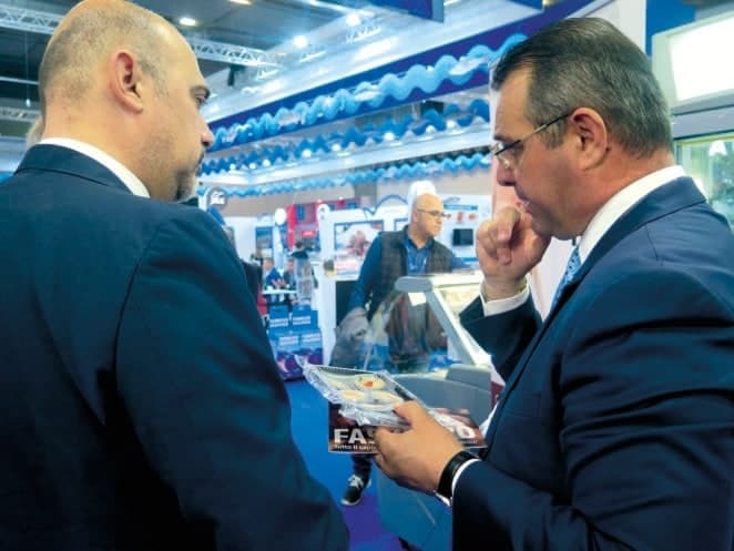 Due persone sfogliano la rivista con l'articolo sul fasolaro allo stand di una fiera